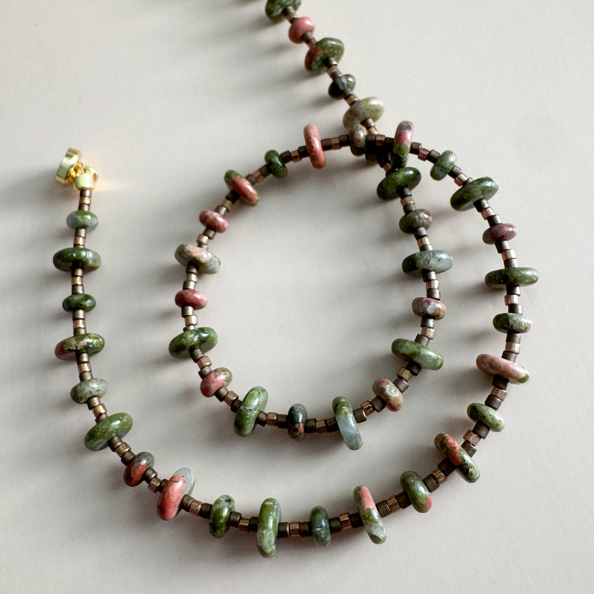 Necklace with unakite beads on a light gray background