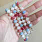 Colorful beaded lanyard held in a hand against a neutral background
