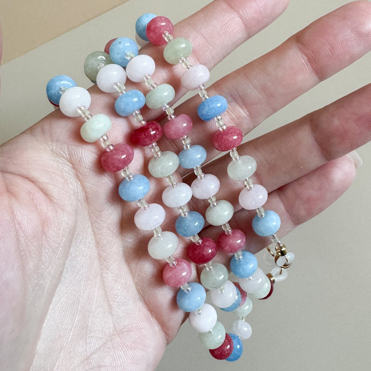 Colorful beaded lanyard held in a hand against a neutral background