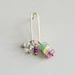 Gold earring with colorful beads on a light gray background
