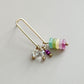 Gold earring with colorful beads on a light gray background