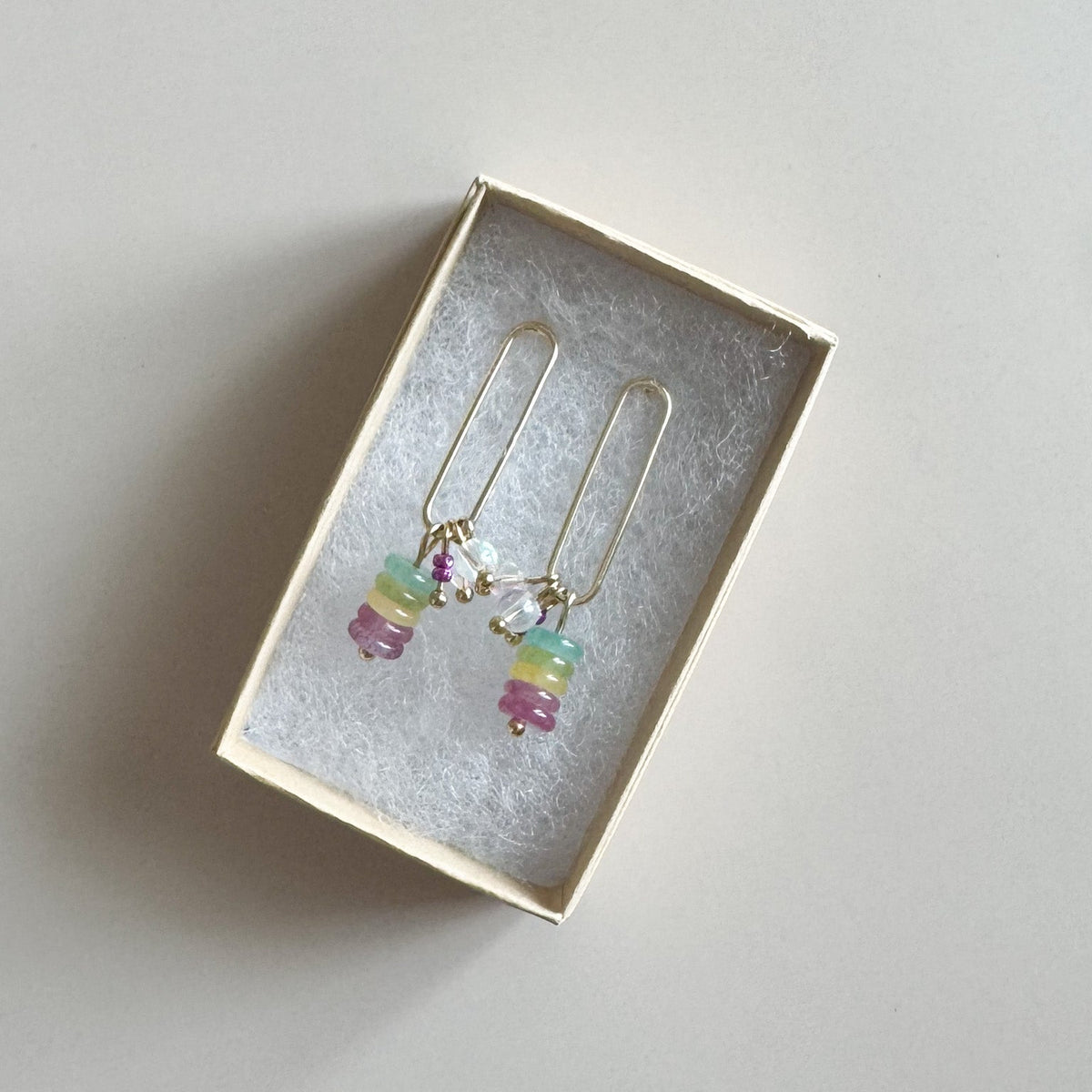 Colorful beaded earrings in a jewelry box on a light gray background