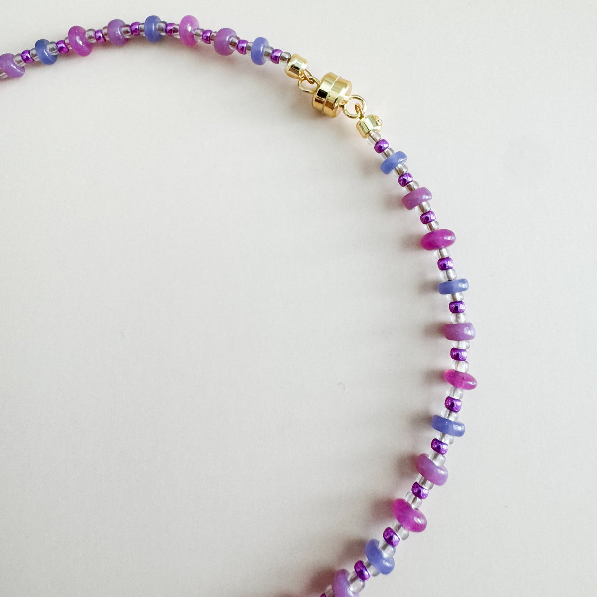 Beaded necklace with a gold magnetic clasp on a light gray background