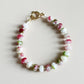 Beaded bracelet with pink, green, and white beads on a light background