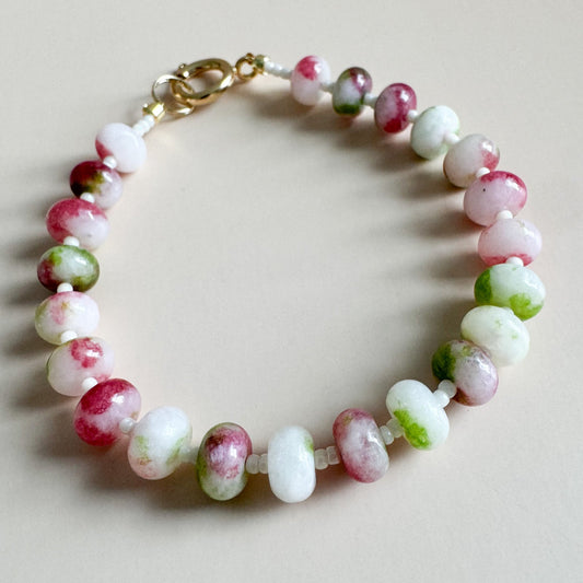 Beaded bracelet with pink, green, and white beads on a light background