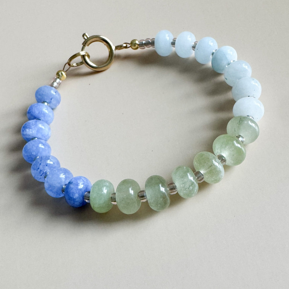 Beaded bracelet with vibrant blue, light blue, and green beads on a light gray background