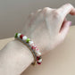 Hand wearing a bracelet with multicolored beads on a neutral background