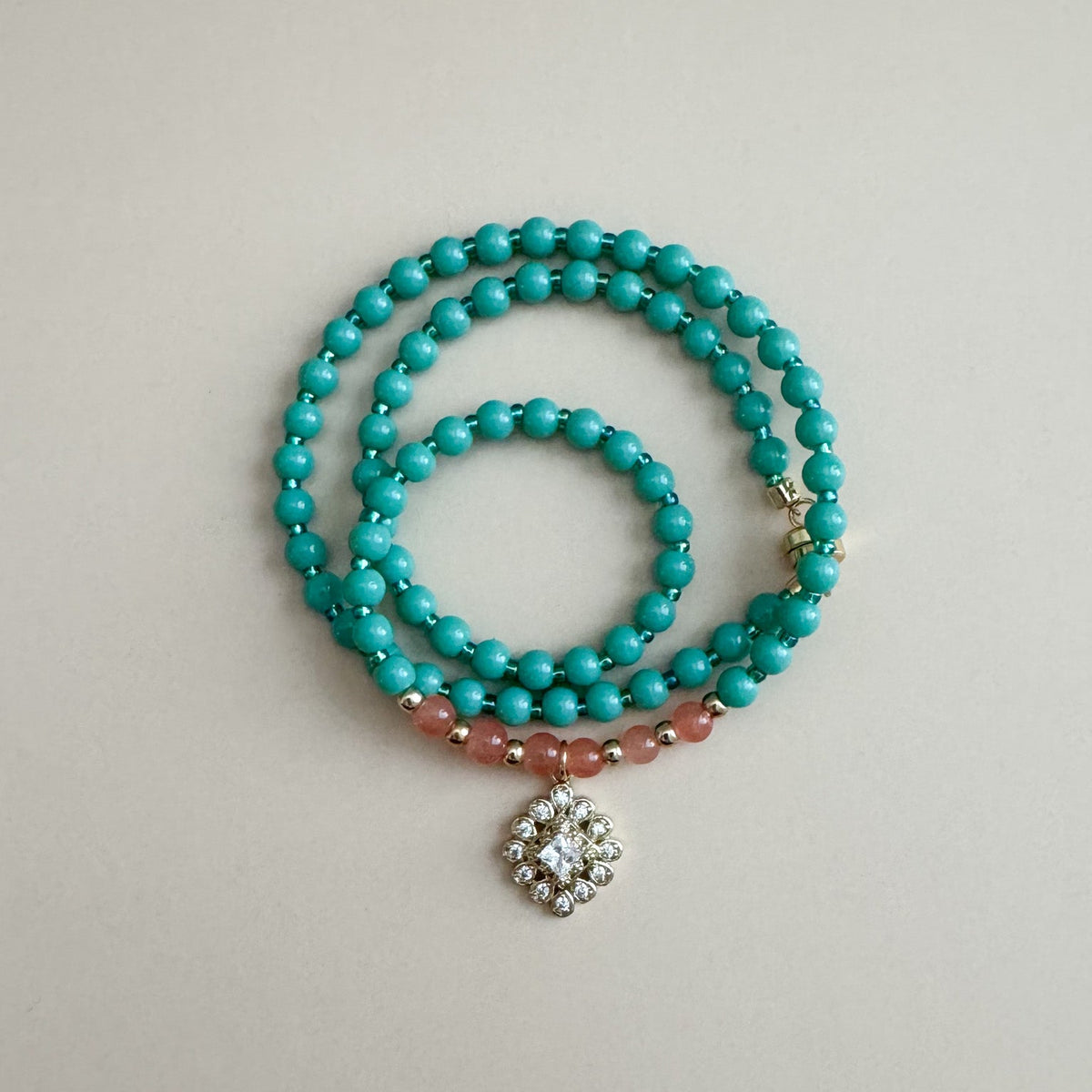 mint green and translucent orange beaded necklace with a decorative pendant on a light gray background