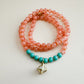 Necklace with translucent orange and mint green beads on a light gray background