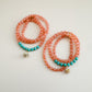 Two beaded bracelets with translucent orange and mint green beads and star charms on a light background